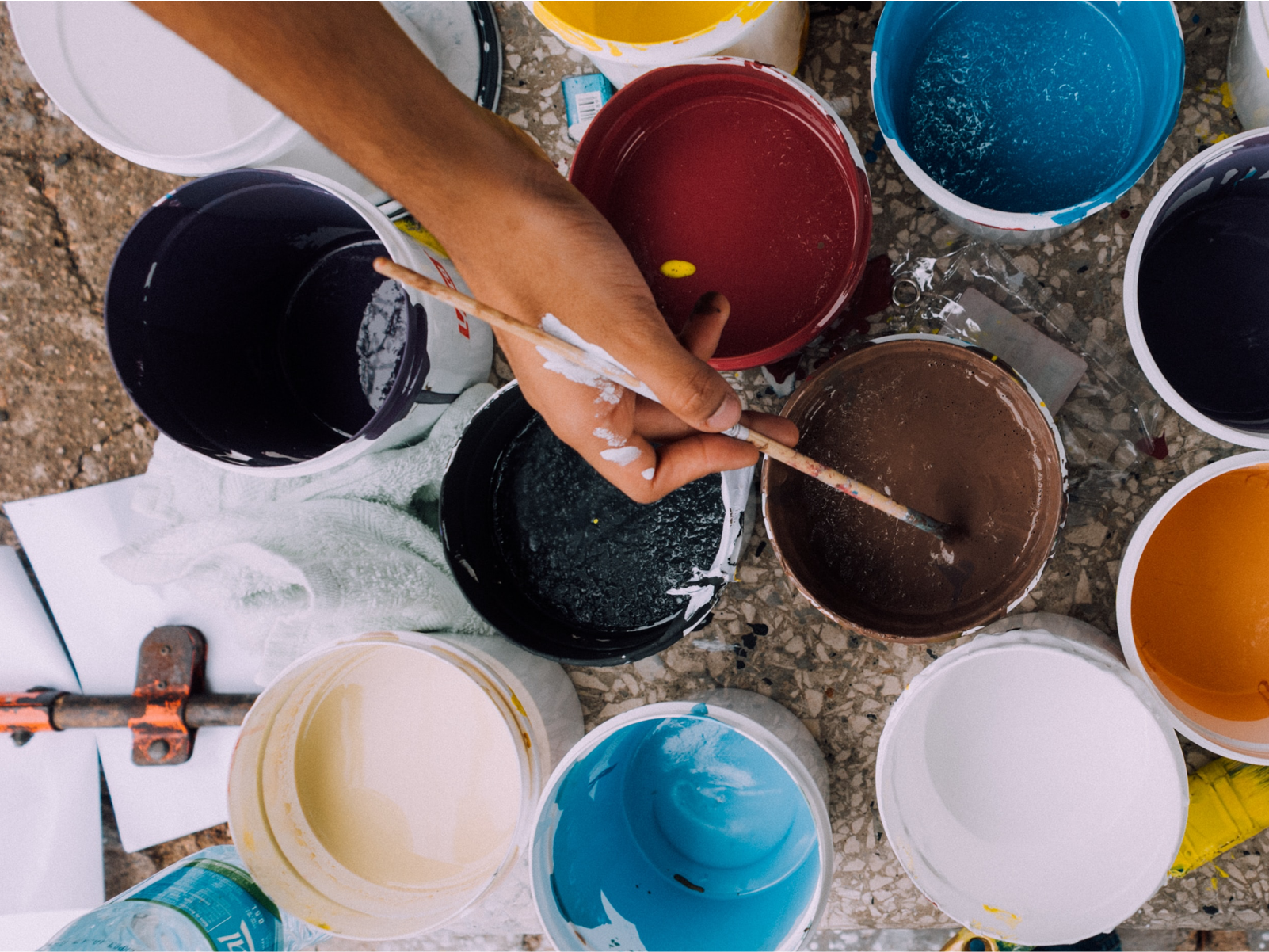 white buckets filled with colorful paints while artist works, viewd from above.