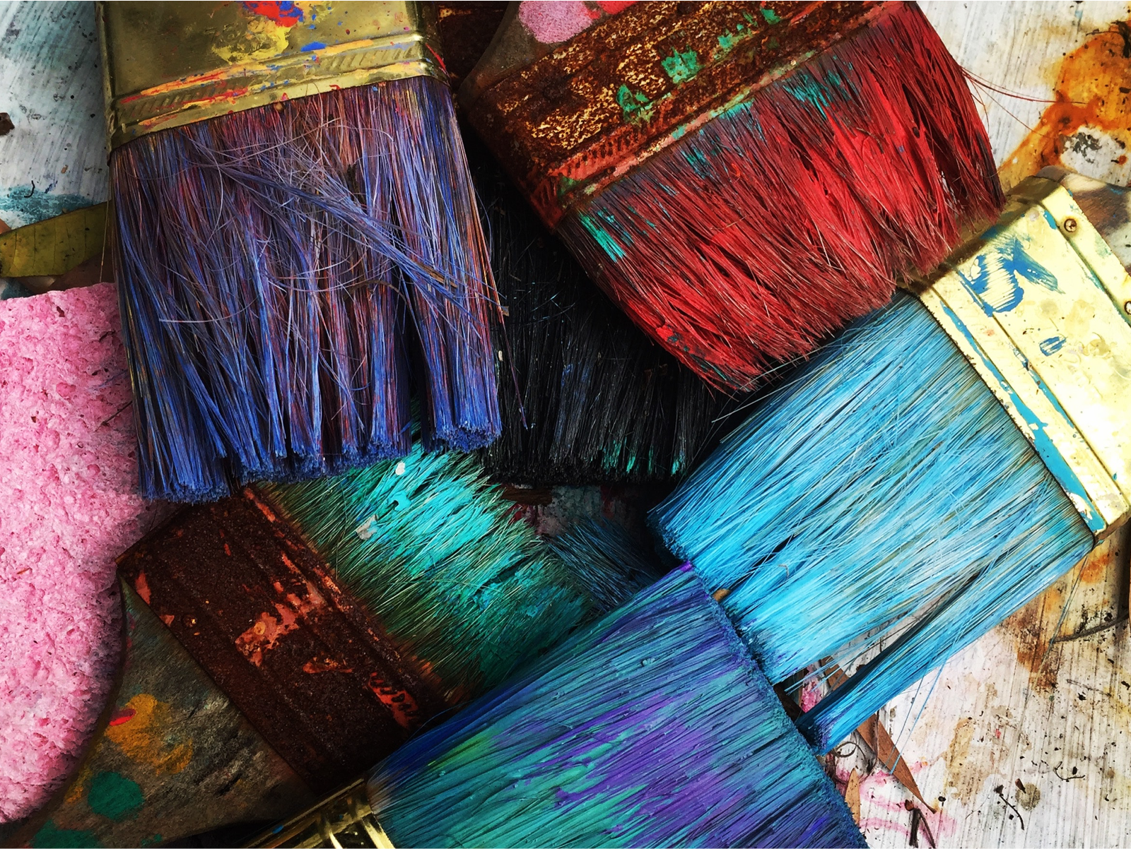 colorful paint covered brush heads on table, viewed from above.